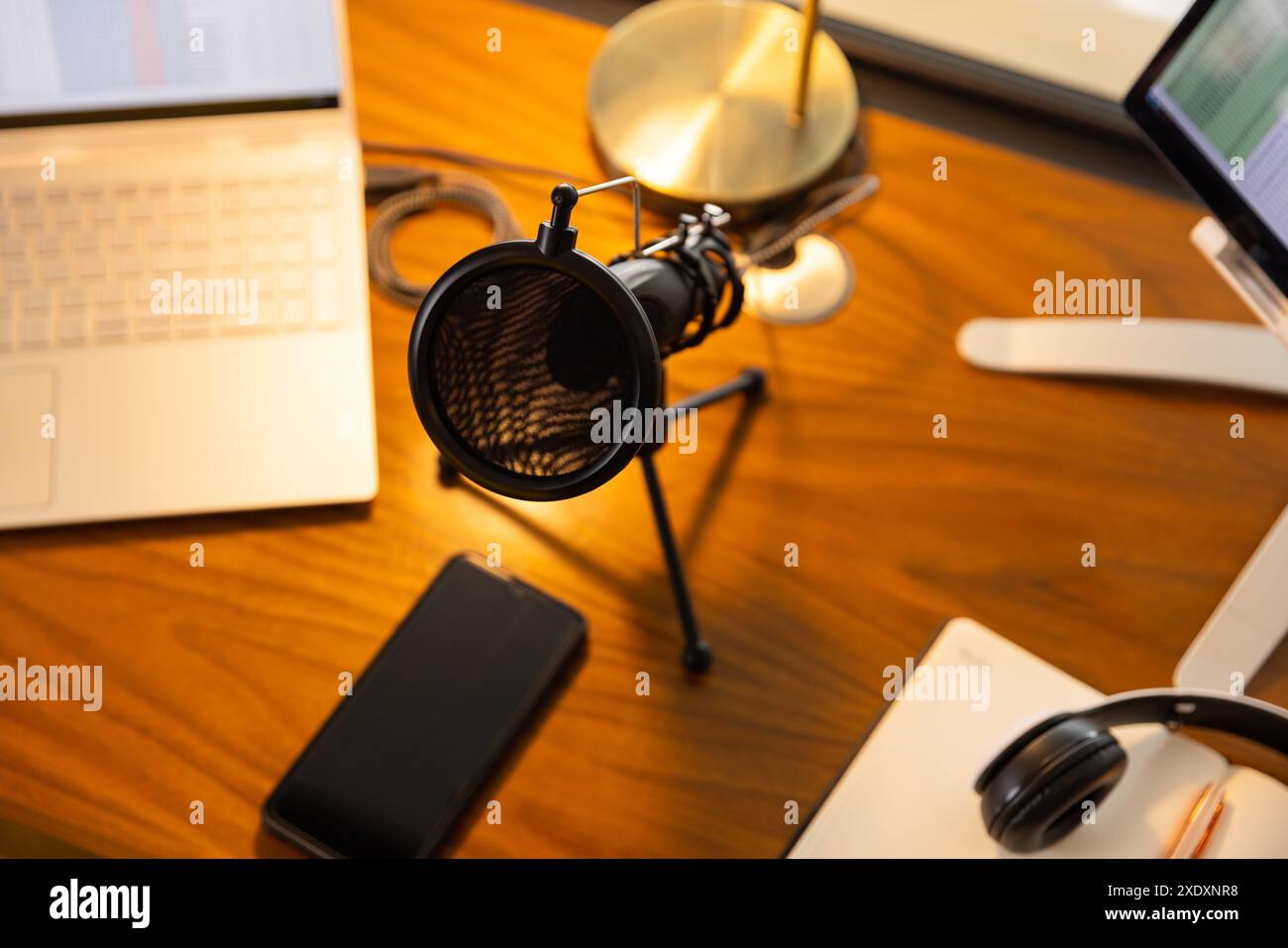 Configurazione podcasting con microfono, computer portatile e smartphone su scrivania in legno, spazio per le copie Foto Stock