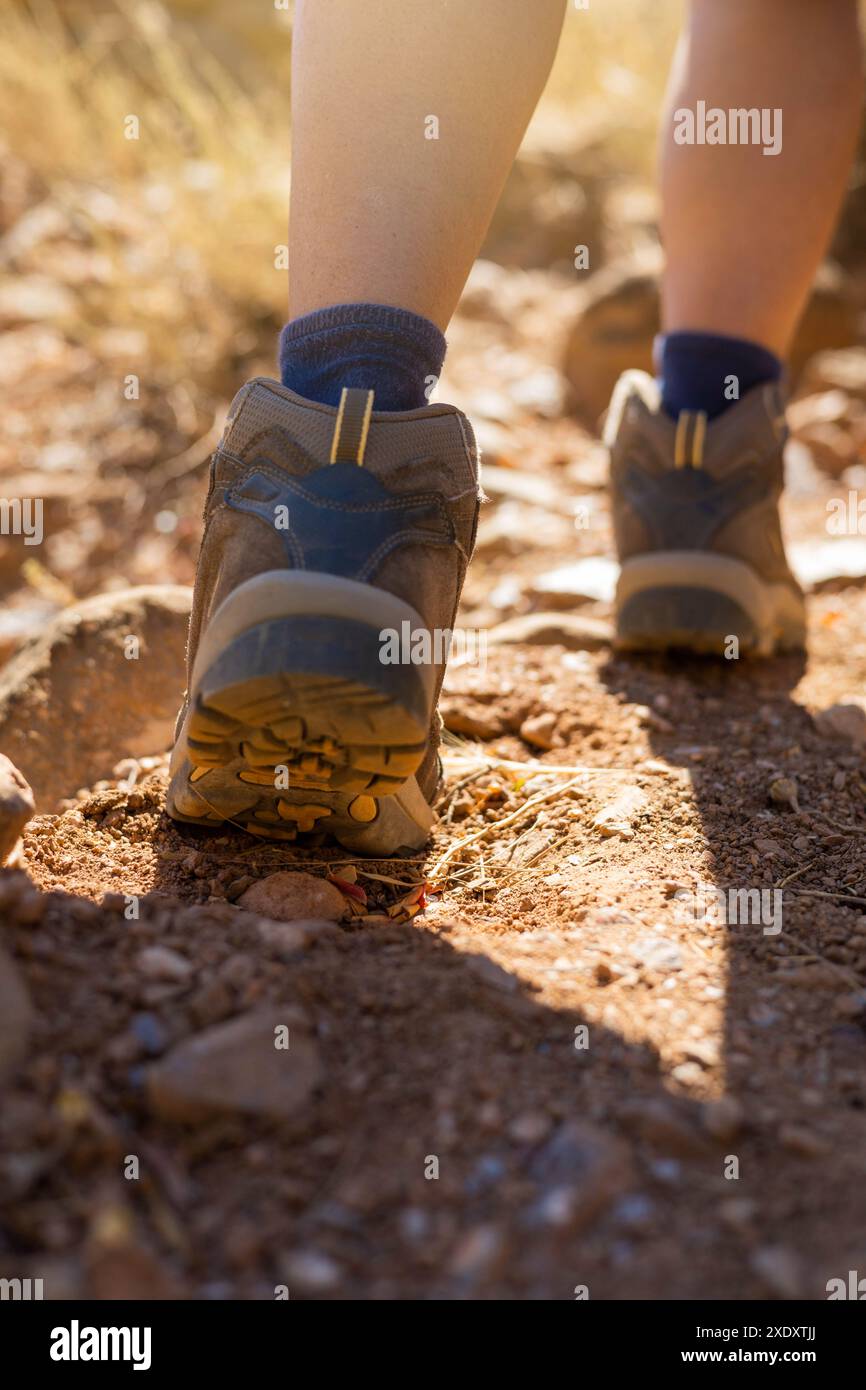 Un primo piano di scarponi da trekking che camminano su un sentiero roccioso, mostrando il terreno accidentato e l'avventura all'aria aperta. Foto Stock