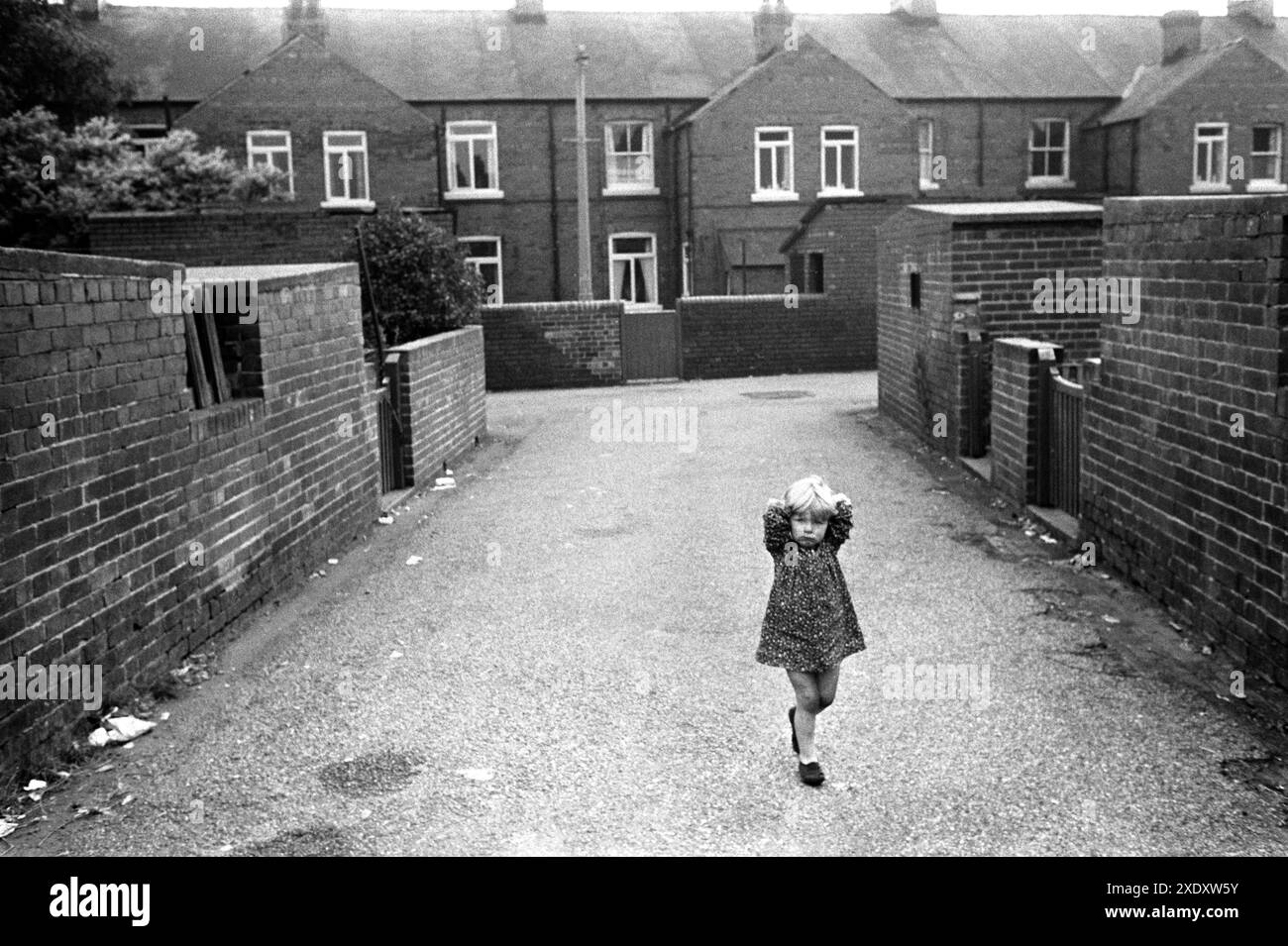 Villaggio di miniere di carbone degli anni '1970 Regno Unito. La ragazza preadolescente con le mani dietro la testa si aggira lungo il "vicolo posteriore", tra le case dei minatori schiena a schiena. Unione nazionale dei lavoratori dei minatori (num) alloggi. Pit Village, South Kirkby, Yorkshire, Inghilterra 1979 HOMER SYKES Foto Stock