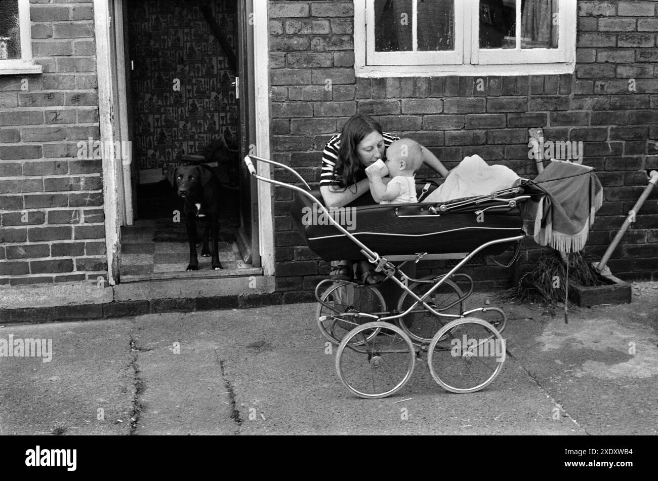 Pit Mining Village vita familiare anni '1970 Gran Bretagna. La signora Carol Backhouse e il bambino Craig in carrozza. Snoopy all'ingresso della loro casa nella tenuta di Northfield. Questo è il retro della loro casa. South Kirkby Colliery, Yorkshire, Inghilterra 1979 HOMER SYKES Foto Stock