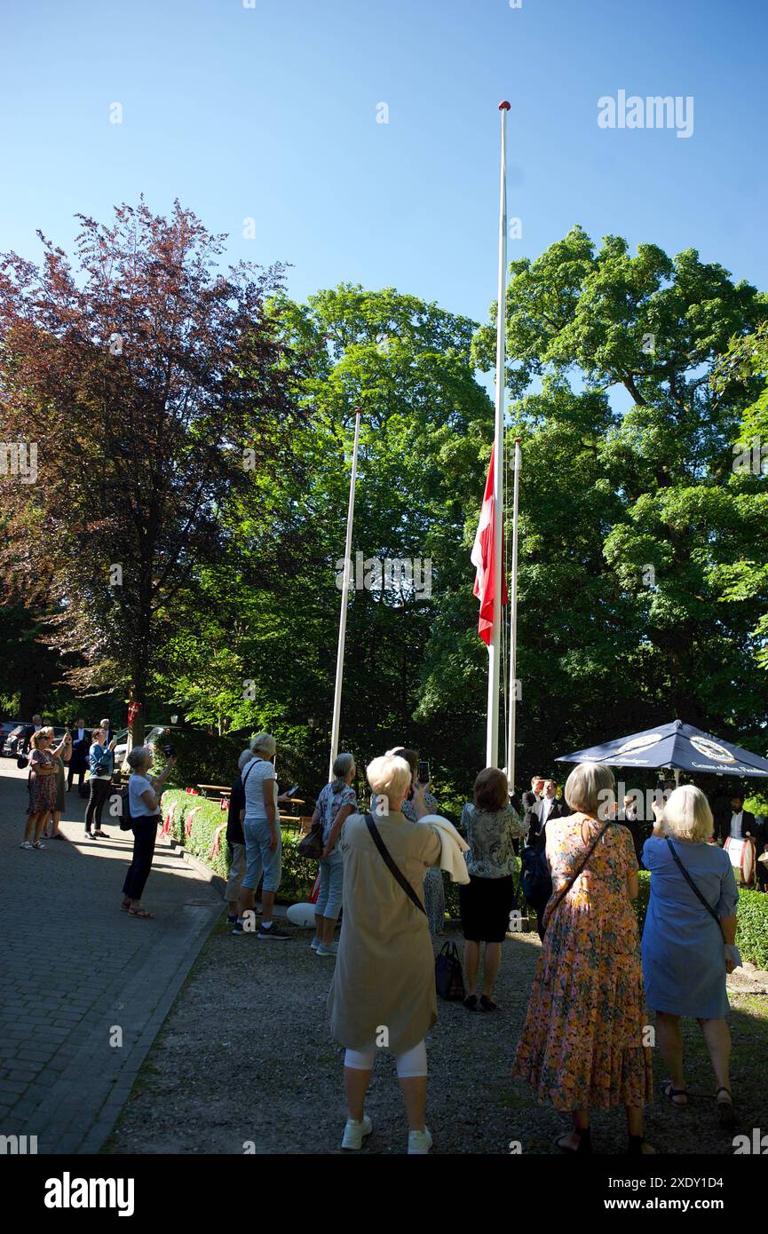 Flensburg, Schleswig-Holstein St. Knudsgilde feiert 854. Jahrestag der Seligsprechung ihres Schutzpatrons Knud Lavard. Gildebrüder hissen die dänische Fahne an der Heimstätte der Knudsgilde, der Knudsborg am Hillig-Water Gang Helligvandsgangen / Munketoft 33. Dazu spielt die Kapelle die dänische Nationalhymne. Aufnahme vom 25.06.2024, Flensburg *** Flensburg, Schleswig Holstein St Knudsgilde celebra il 854° anniversario della beatificazione del suo patrono, i fratelli Knud Lavard Guild issano la bandiera danese nella casa di Knudsgildes, il Knudsborg a Hillig Water Gang Helligvandsgangen Munk Foto Stock