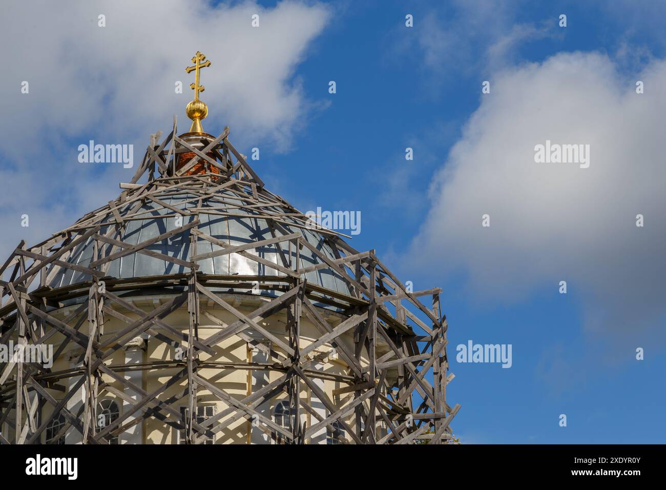 Impalcature in legno grigio su una cupola della chiesa cristiana russa alla luce del giorno sul cielo blu con nuvole bianche Foto Stock
