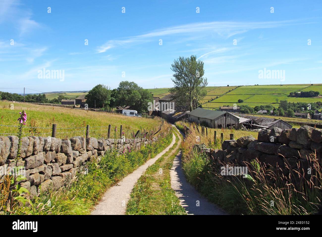 Stretta strada di campagna che scende da una collina nella panoramica campagna dello yorkshire occidentale vicino al villaggio di colden a calderdale, nello yorkshire occidentale Foto Stock