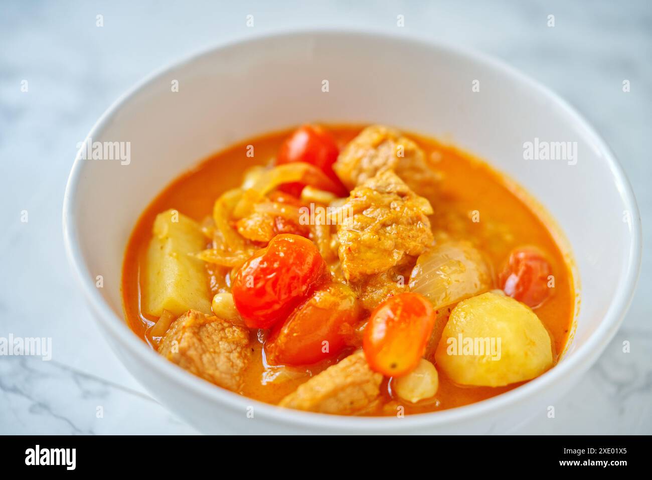 Il curry tradizionale thailandese chiamato Pork Masaman curry, il curry in muraman è in ciotola bianca su un tavolo di marmo. Immagine ravvicinata del cibo tailandese. Foto Stock