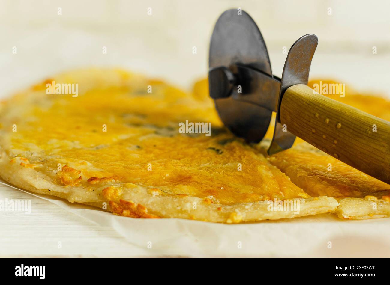Primo piano. Tagliare la pizza appena sfornata con un tagliapasta. Foto Stock