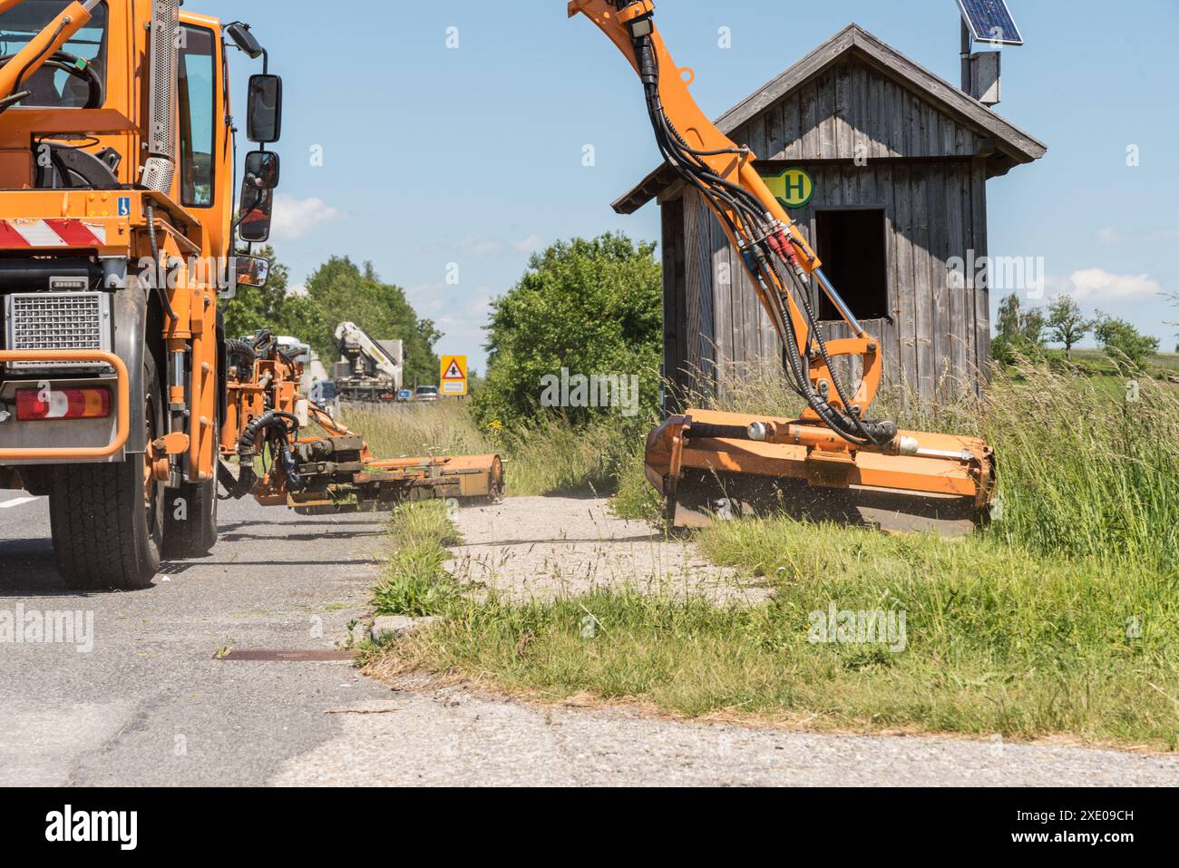 Falciatura eseguita dal reparto di manutenzione stradale sul lato della strada - sicurezza stradale Foto Stock