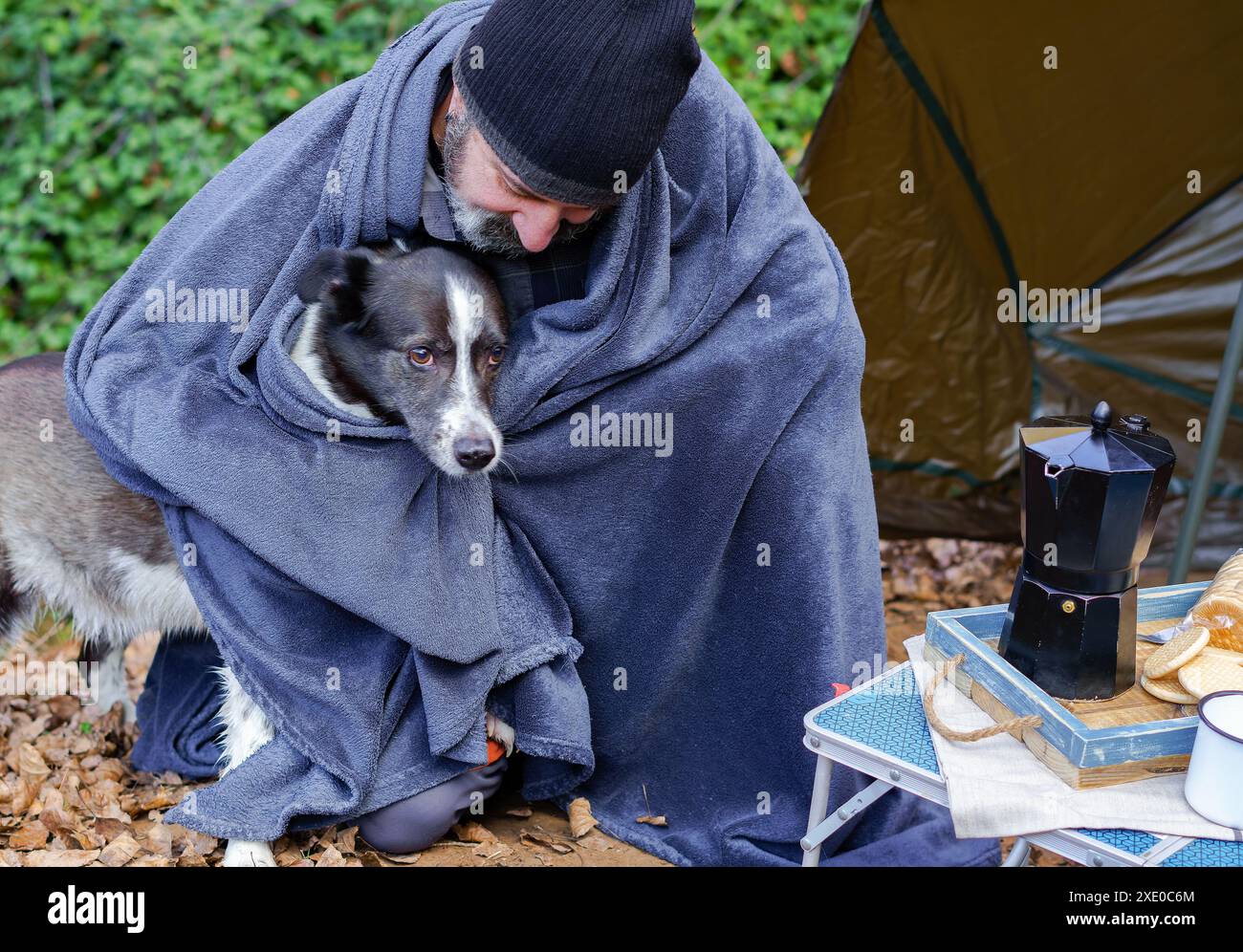 Uomo in campeggio coperto di una coperta con il suo cane Foto Stock Uomo in campeggio coperto di una coperta con il suo cane Foto Stock