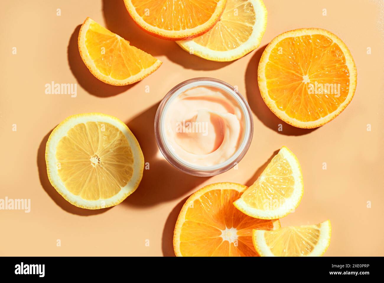 Sbiancare la crema viso con acidi di frutta e vitamina C e fette di agrumi di limone e arancio, vista dall'alto, layout creativo. Pelle naturale anti-invecchiamento per auto Foto Stock