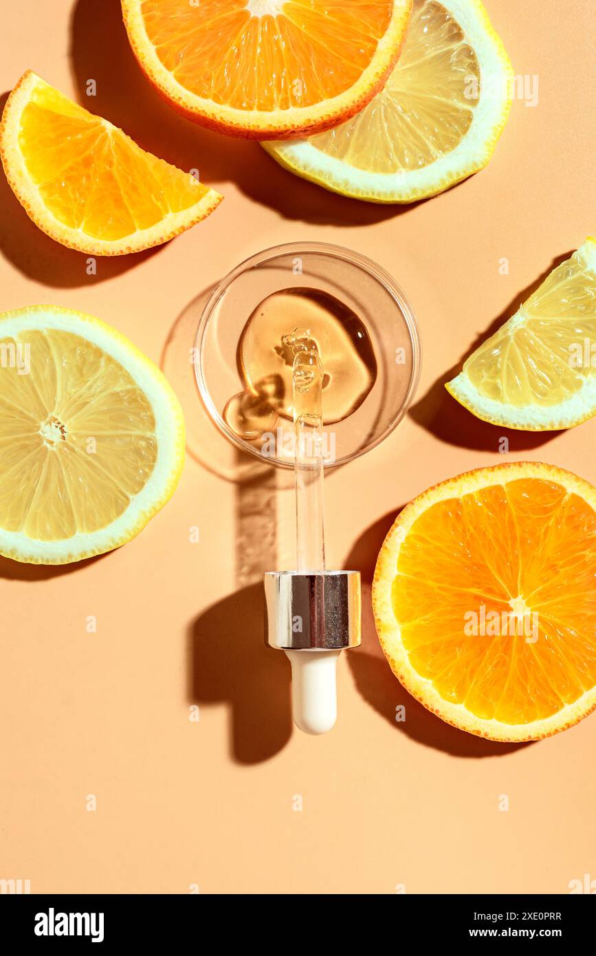Contagocce per siero di bellezza con acidi di frutta e vitamina C e fette di agrumi di limone e arancia, vista dall'alto, layout creativo. Pelle naturale anti-invecchiamento CA Foto Stock