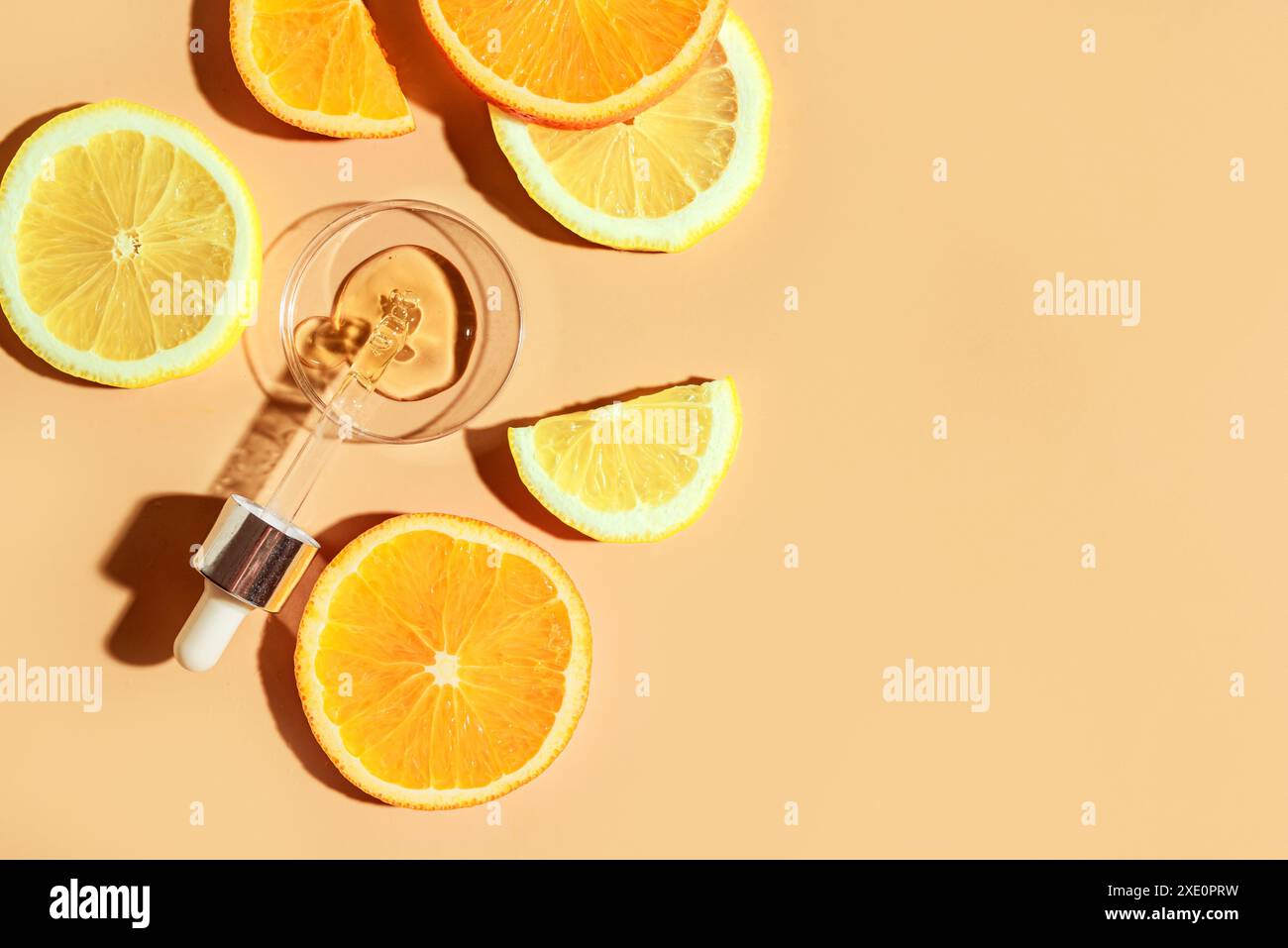 Contagocce per siero di bellezza con acidi di frutta e vitamina C e fette di agrumi di limone e arancia, vista dall'alto, layout creativo, spazio di copia. Naturale anti-ag Foto Stock