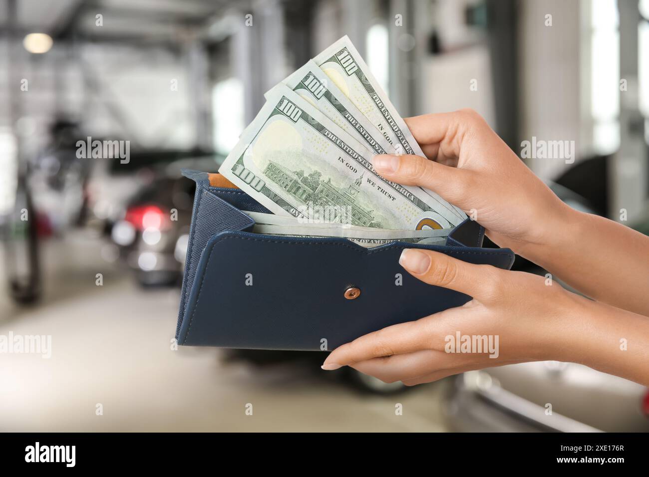 Donna che prende soldi dal portafoglio in un negozio di automobili, primo piano. Comprare la macchina Foto Stock