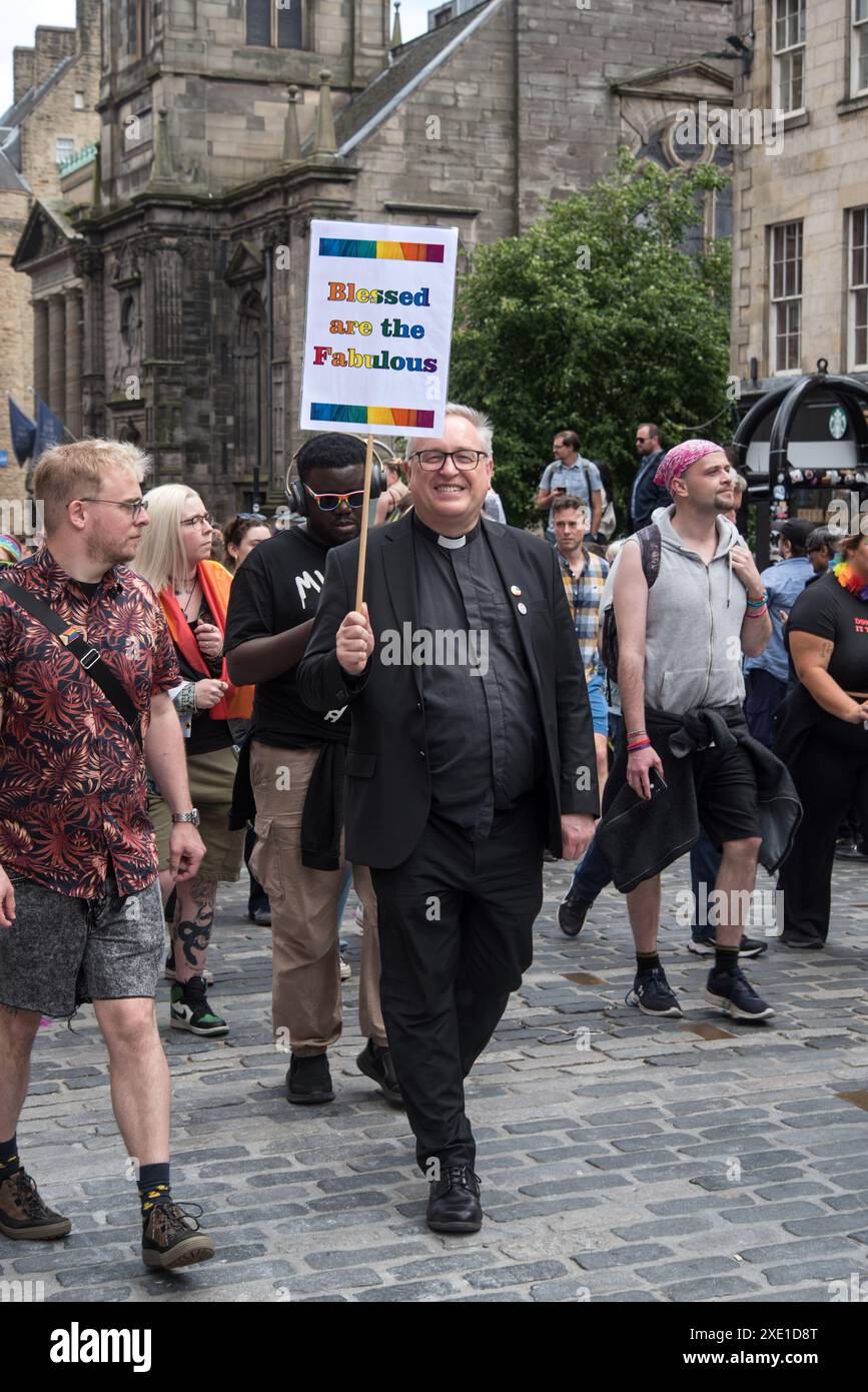 Membro del clero con un cartello "Bessed Are the Fabulous", camminando lungo il Royal Mile durante l'Edinburgh Pride 2024. Foto Stock