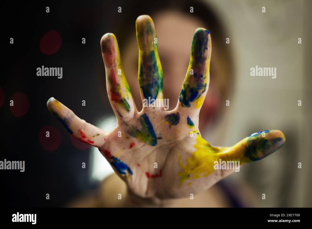 Foto vibrante della mano di un'artista femminile ricoperta di vernice multicolore, che enfatizza il fascino artistico e la gioia della pittura. Foto Stock