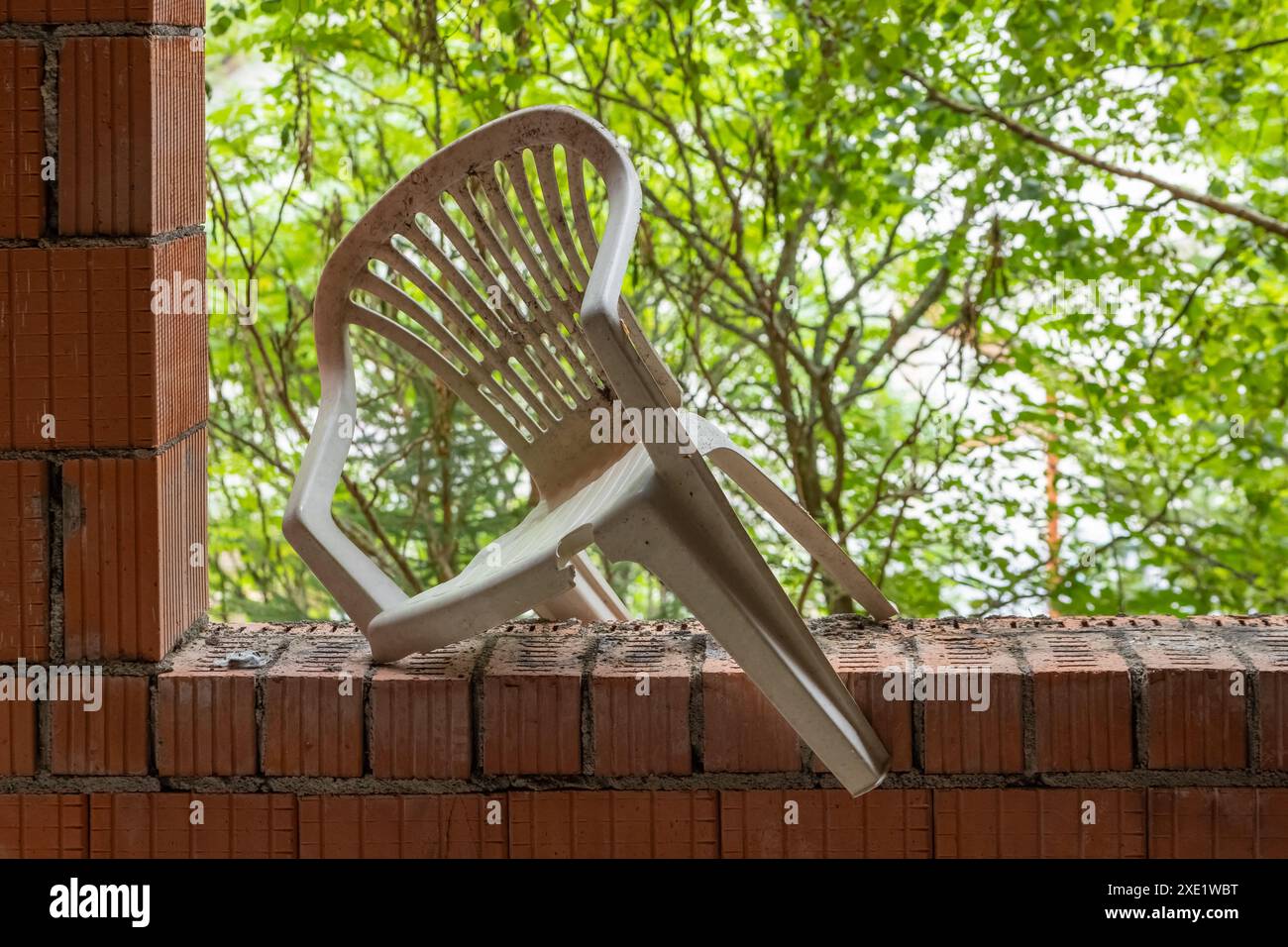 Una sedia da giardino rotta in una casa incompiuta Foto Stock