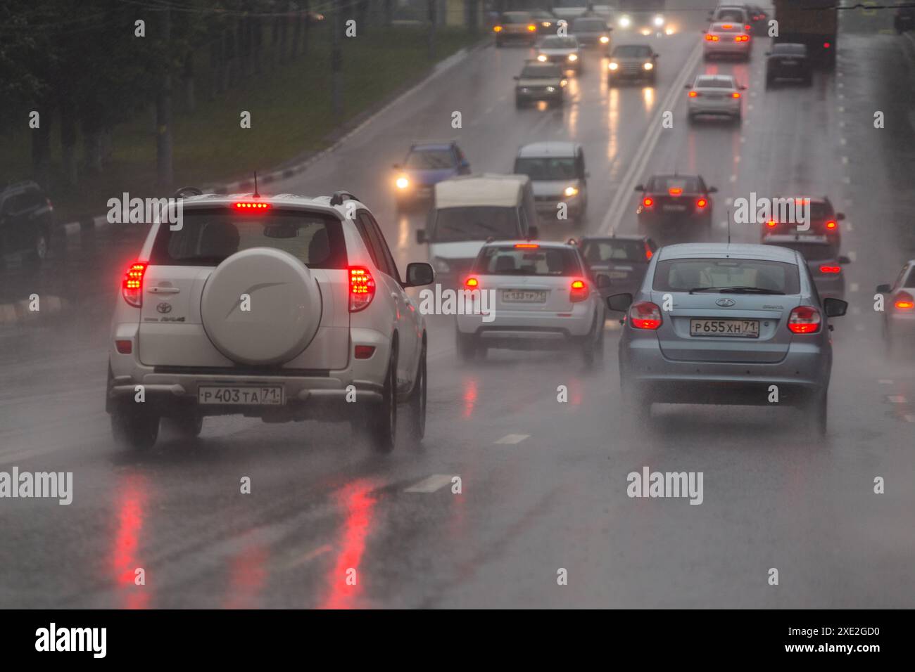 Auto che si muovono su strade asfaltate bagnate durante le forti piogge cadono durante il giorno estivo a Tula, Russia Foto Stock