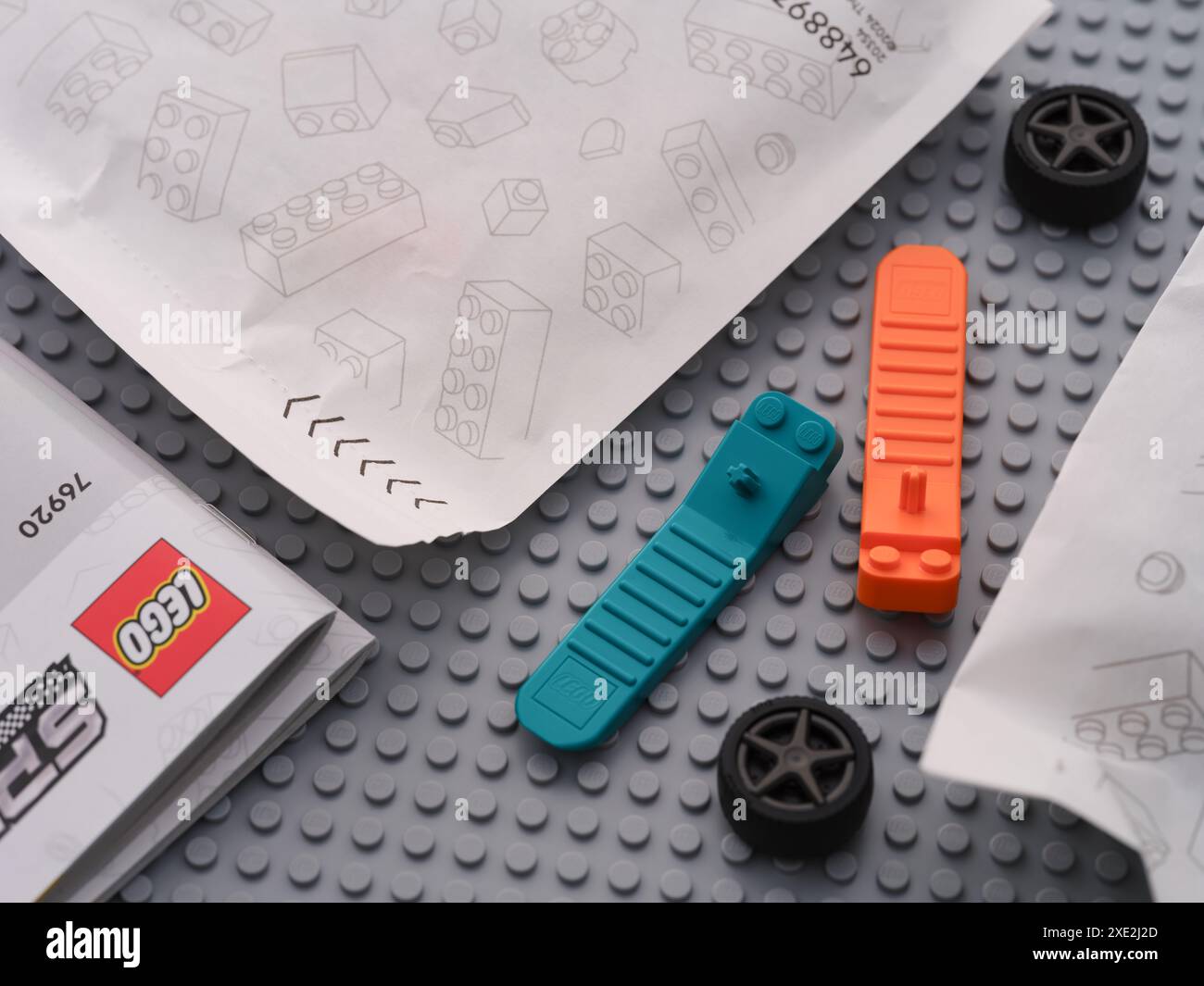 Tambov, Federazione Russa - 22 giugno 2024 separatori di mattoni LEGO e ruote tra le istruzioni e sacchetti di carta con pezzi LEGO su una base grigia Foto Stock