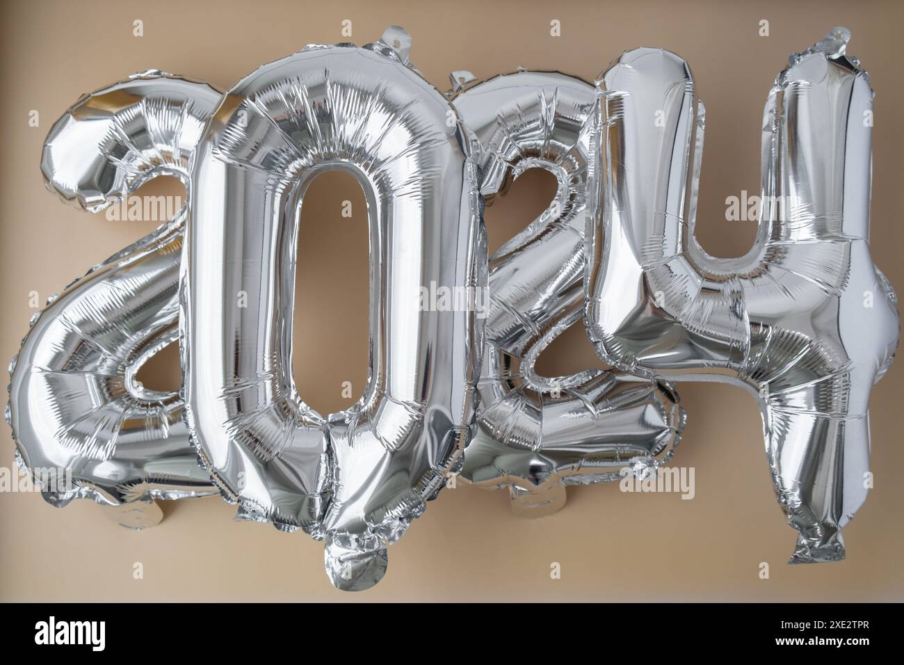 Palloncino Silver foil numero 2024 per festeggiare l'anno nuovo su sfondo beige neutro. Concetto di auguri di buon anno. Duemila Foto Stock