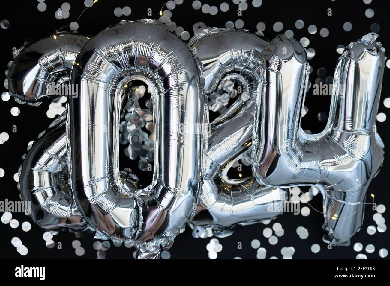 Felice anno nuovo 2024 palloncini metallizzati con coriandoli su sfondo nero scuro. Biglietto d'auguri con palloncini in lamina d'argento, numeri Christm Foto Stock