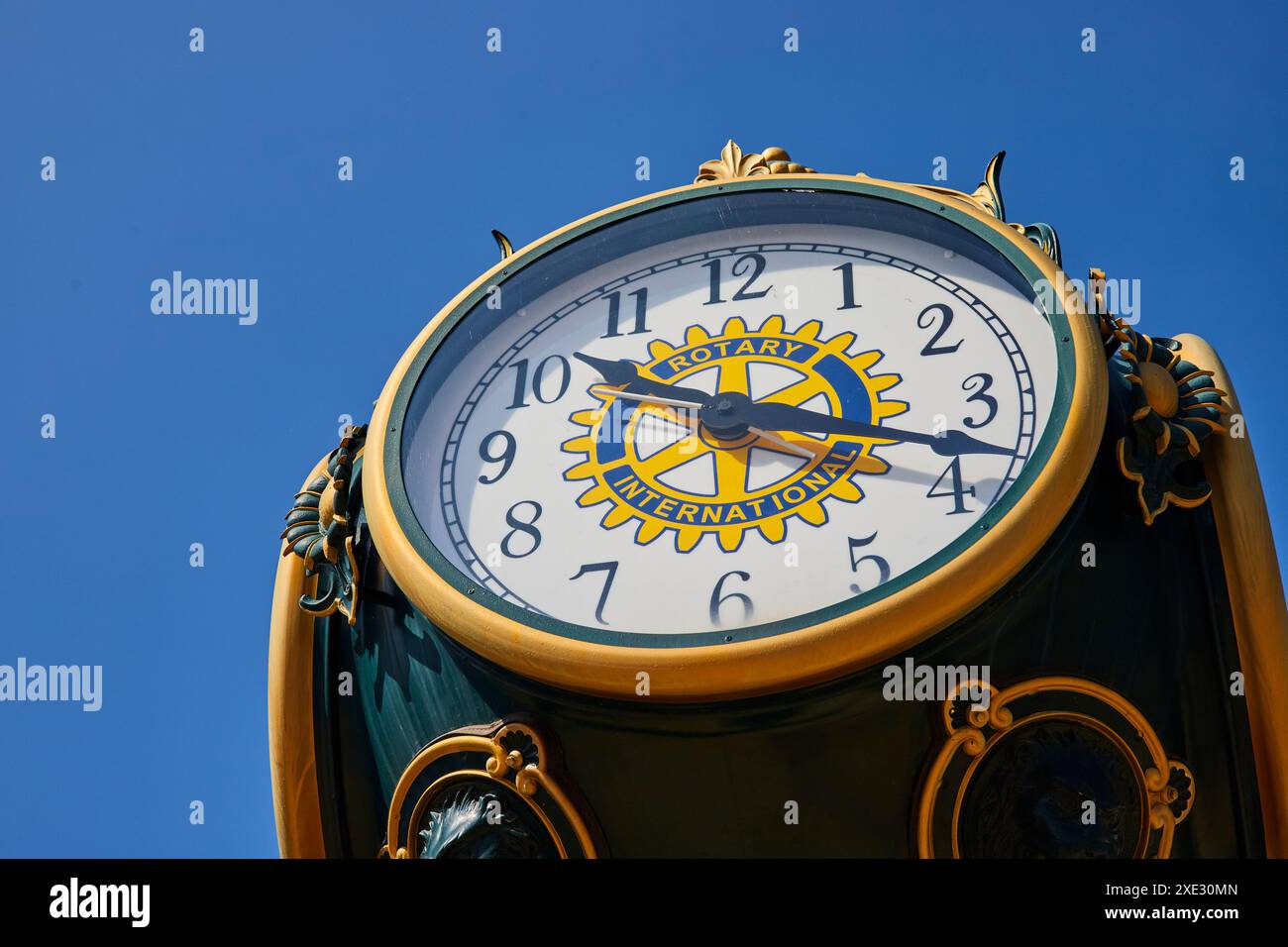 Orologio pubblico ornato con simbolo rotativo rivolto verso l'alto contro il cielo blu Foto Stock