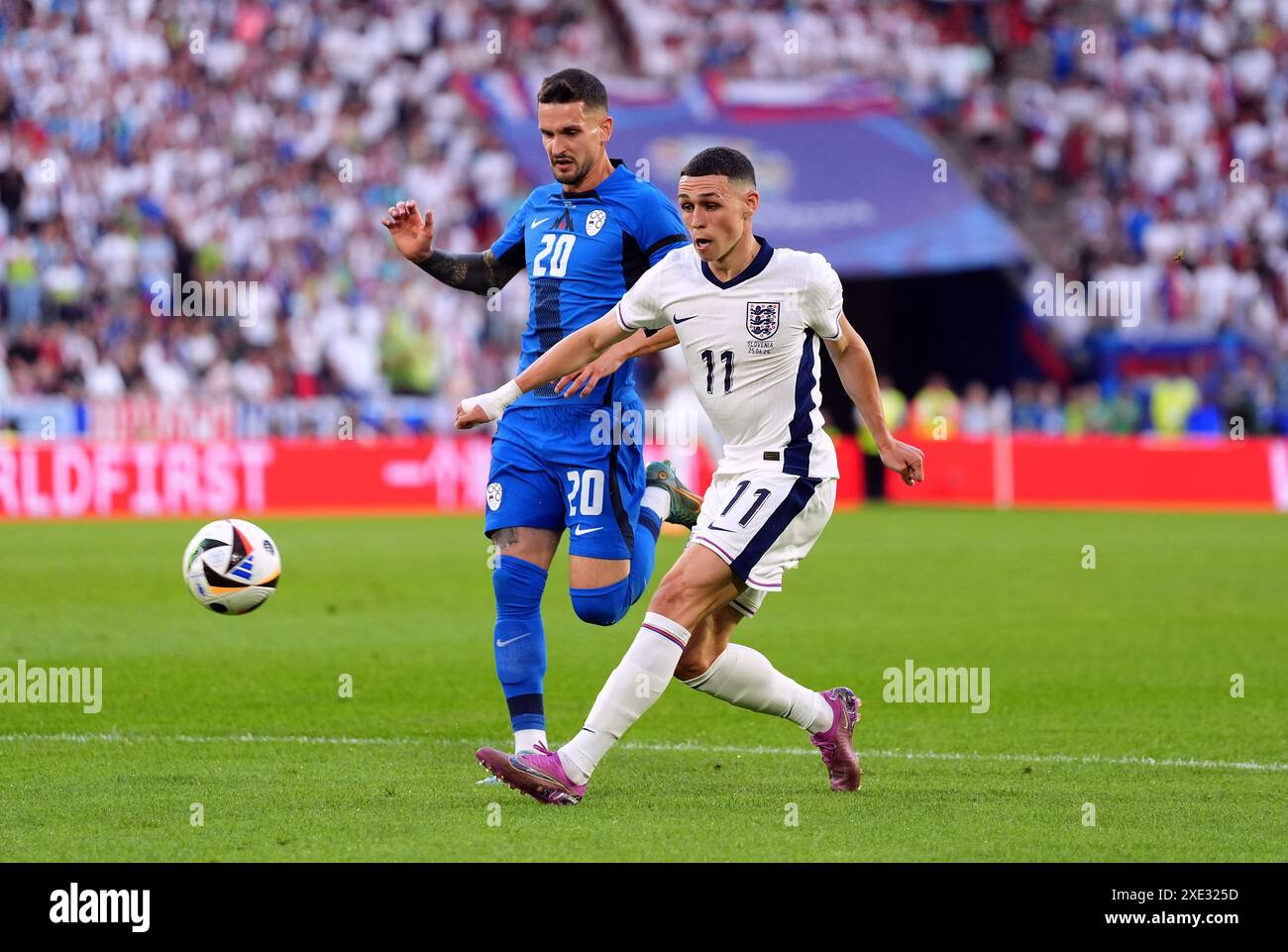 Phil Foden inglese e Petar Stojanovic sloveno (a sinistra) durante la partita UEFA Euro 2024 del gruppo C allo stadio di Colonia, in Germania. Data foto: Martedì 25 giugno 2024. Foto Stock