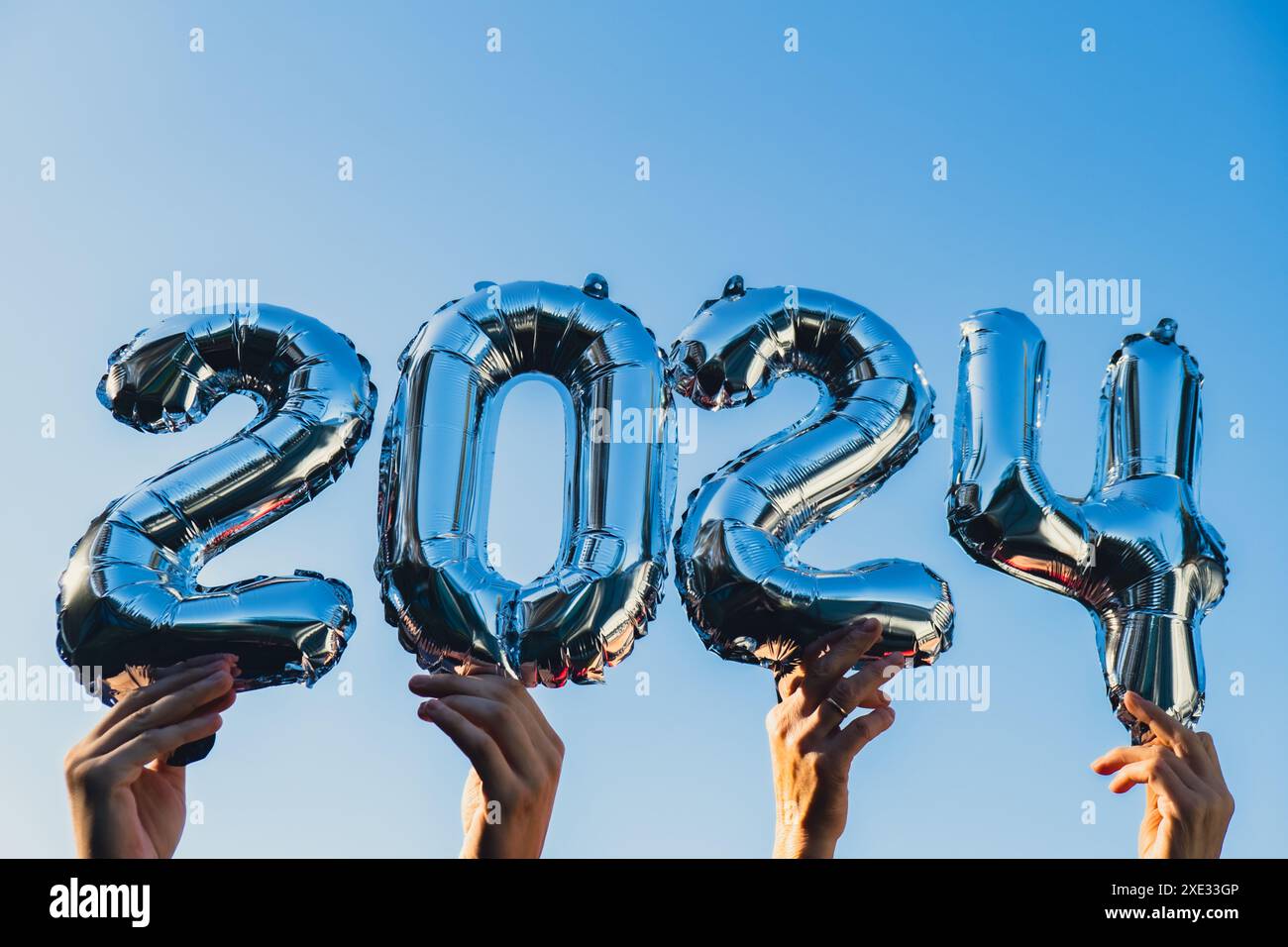 Felice anno nuovo 2024 palloncini metallici su sfondo blu. Biglietto d'auguri con palloncini d'argento, numeri natalizi Foto Stock