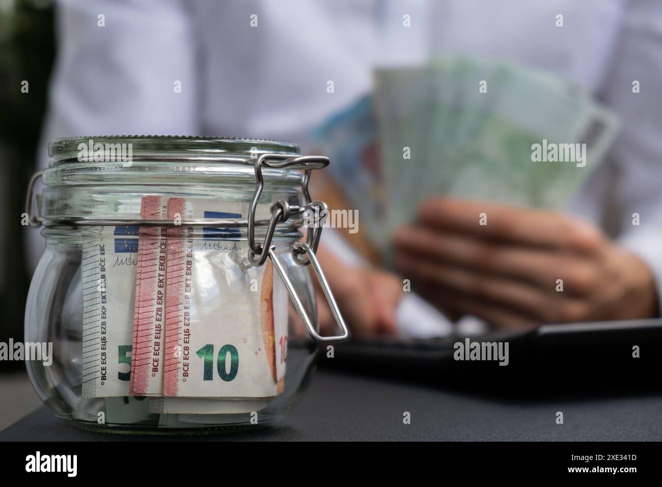 Euro Banknote risparmio in vaso di vetro. Uomo irriconoscibile consumo moderato su calcolatrice e economia raccogliere denaro Consigli Foto Stock