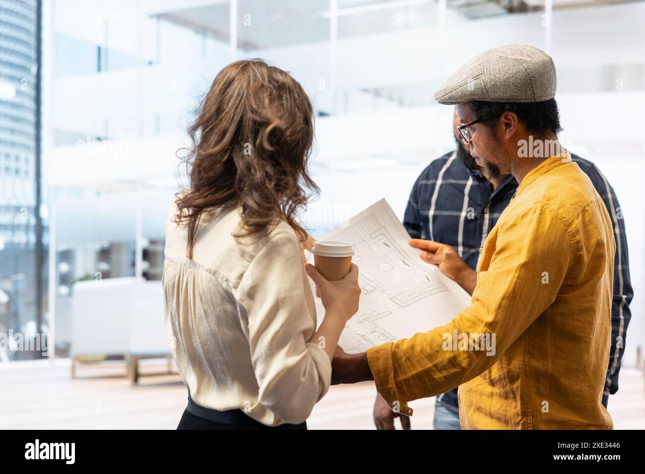 Agente immobiliare che fornisce consulenza ai clienti in merito al trasferimento e al leasing di uffici, esamina progetti dettagliati e discute del design architettonico della nuova proprietà. Negoziazione del contratto. Foto Stock