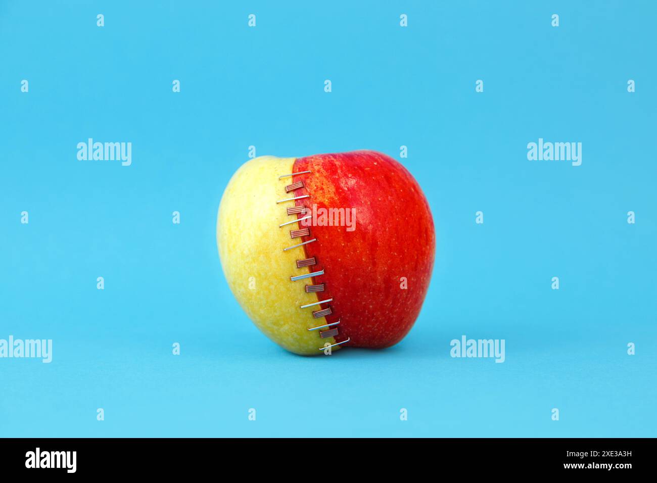 Due mele tagliate a metà (nonna smith e braeburn), rosse e verdi cucite insieme a zinco e rame Foto Stock