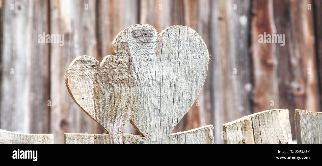 A forma di cuore in una recinzione di legno. Sfondo rustico con cuori scolpiti in legno. Cinghiale a forma di cuore Foto Stock