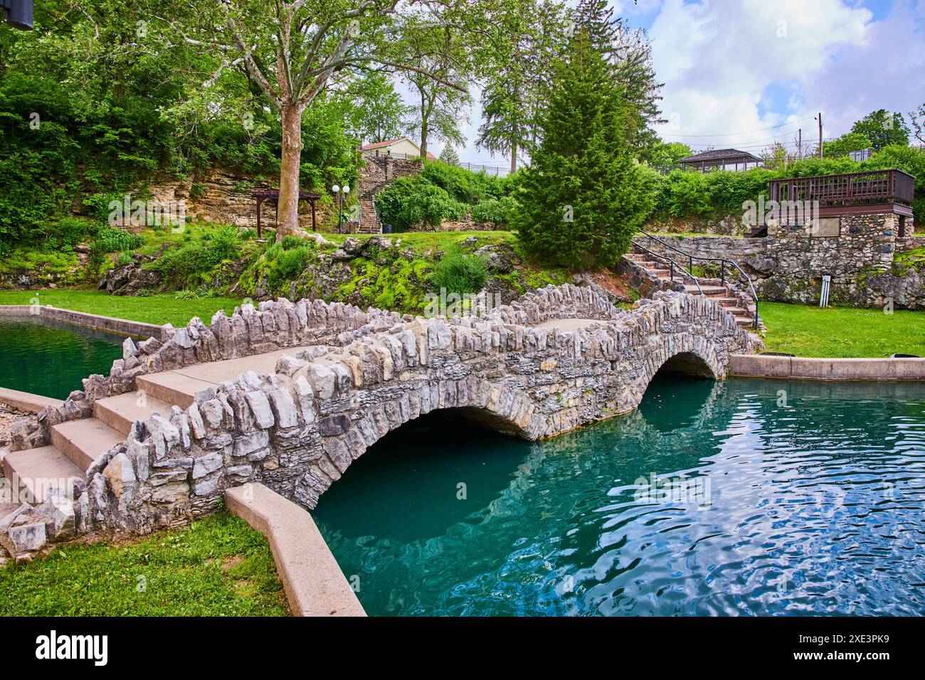 Ponte di pietra e gazebo nei lussureggianti giardini sommersi, prospettiva a livello degli occhi Foto Stock
