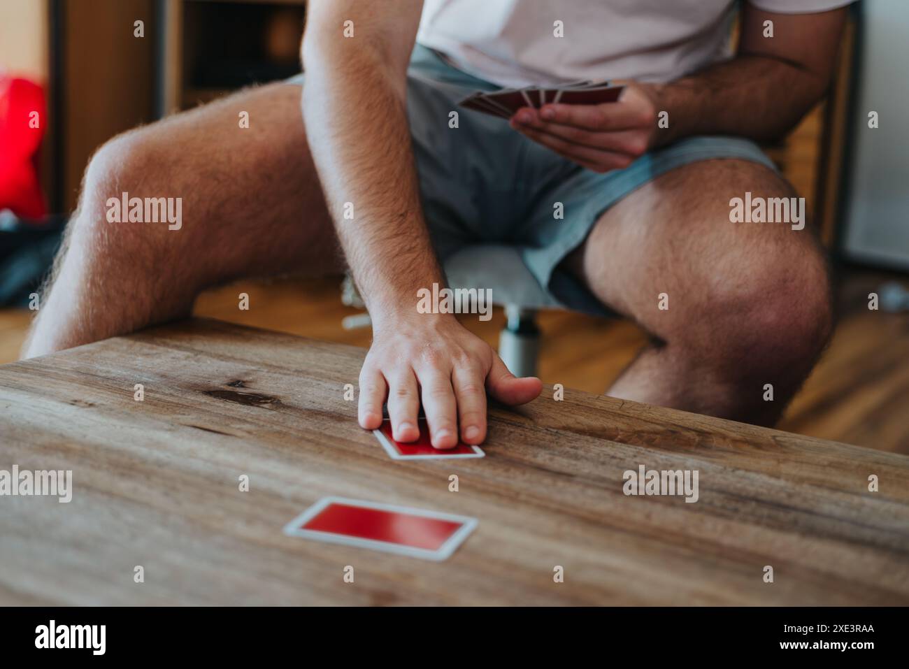 Uomo che si diverte a giocare a carte a casa, si rilassa e si diverte a giocare in modo amichevole Foto Stock