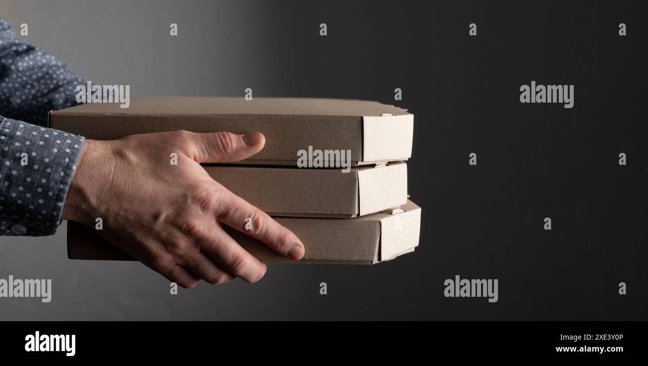 Le mani maschili caucasiche reggono la vista laterale di tre scatole per pizza con spazio per le copie Foto Stock