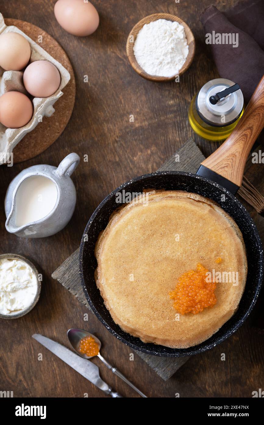 Frittelle di cucina tradizionale russa. Pancake sottili serviti con caviale rosso su un tavolo di legno. Vista dall'alto sfondo piatto. Foto Stock