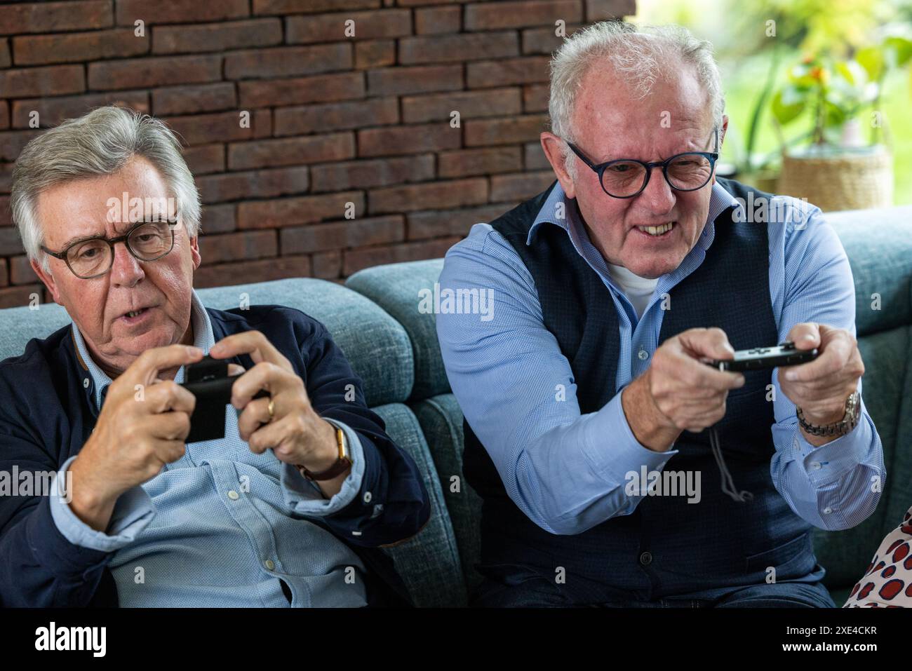 Gioiosa rivalità: Amici senior impegnati in videogiochi Foto Stock