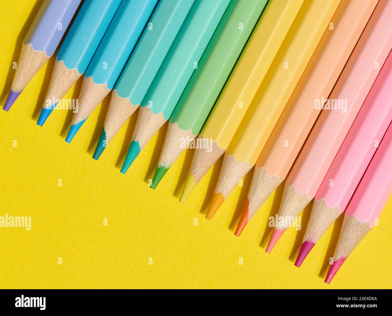 Matite in legno multicolore su sfondo giallo, vista dall'alto Foto Stock
