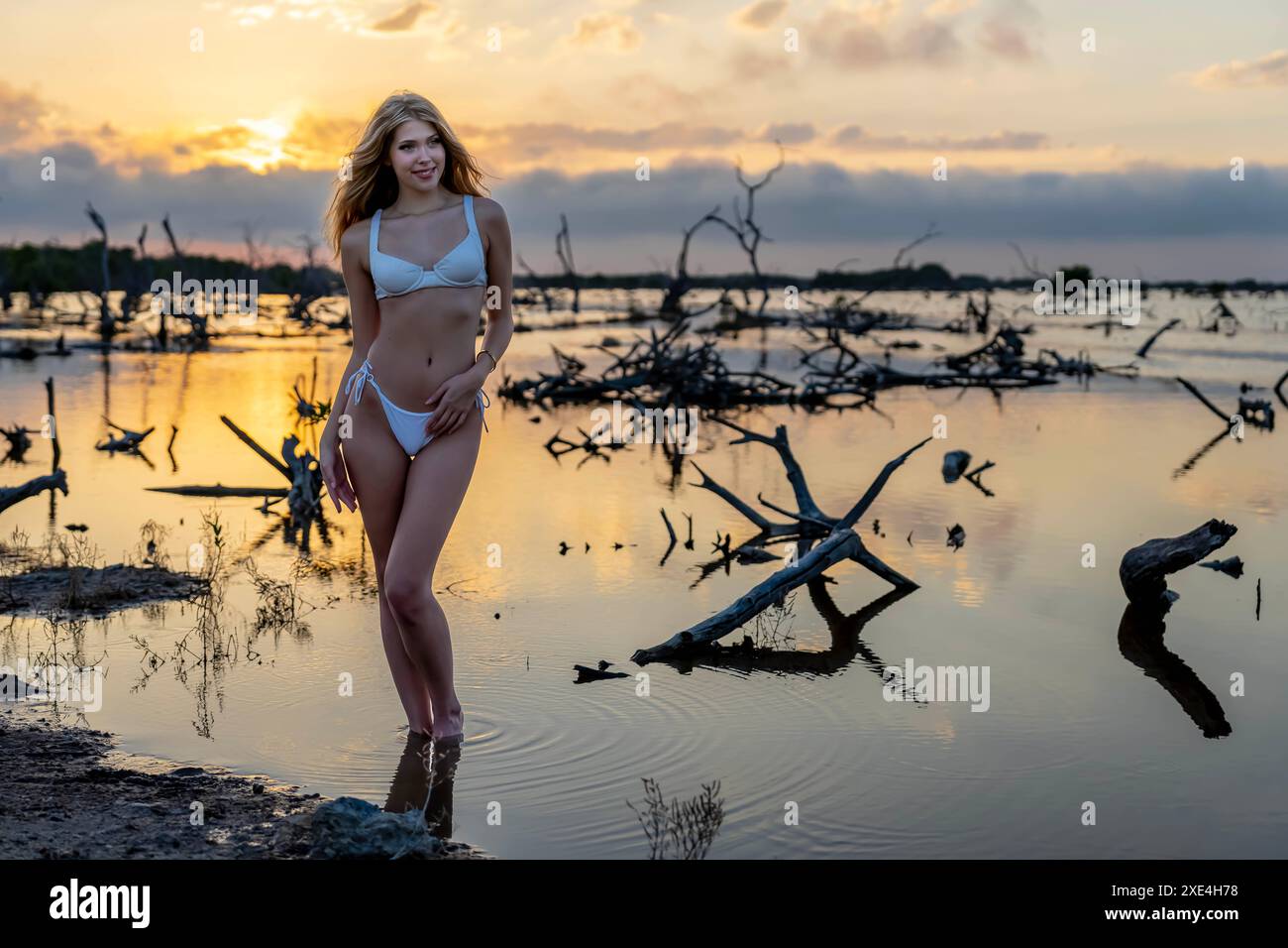 Tranquillità tropicale: La bellezza radiosa colpisce una posa nel lussureggiante paesaggio messicano mentre i tramonti dello Yucatan dipingono il cielo Foto Stock