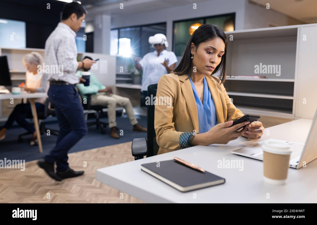 Utilizzo di smartphone, donna d'affari che lavora alla scrivania in un ambiente di lavoro molto affollato Foto Stock