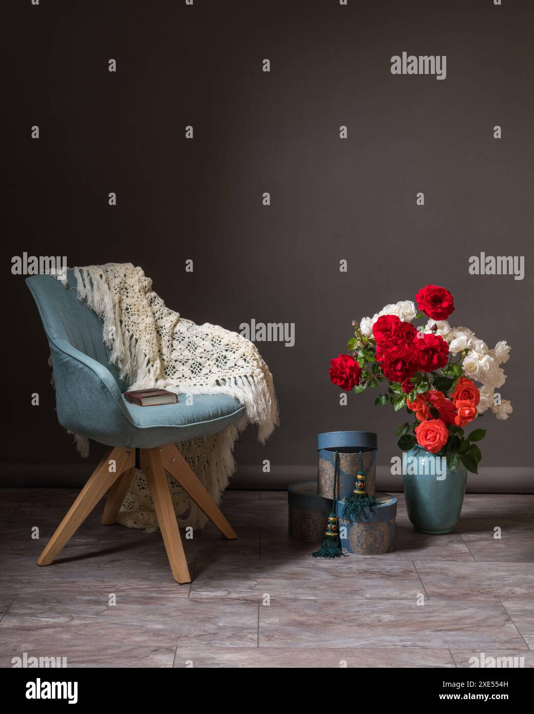 Design del cratere. Zona foto. C'è una sciarpa bianca su una comoda sedia blu. Un grande vaso si erge su una pentola con enormi mazzi di fiori. Confezioni regalo Foto Stock