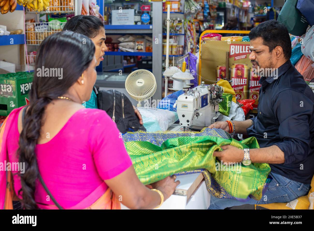Sarto indiano che parla con le sue due clienti femminili vestono a Sari. Piccola India, Singapore. Foto Stock