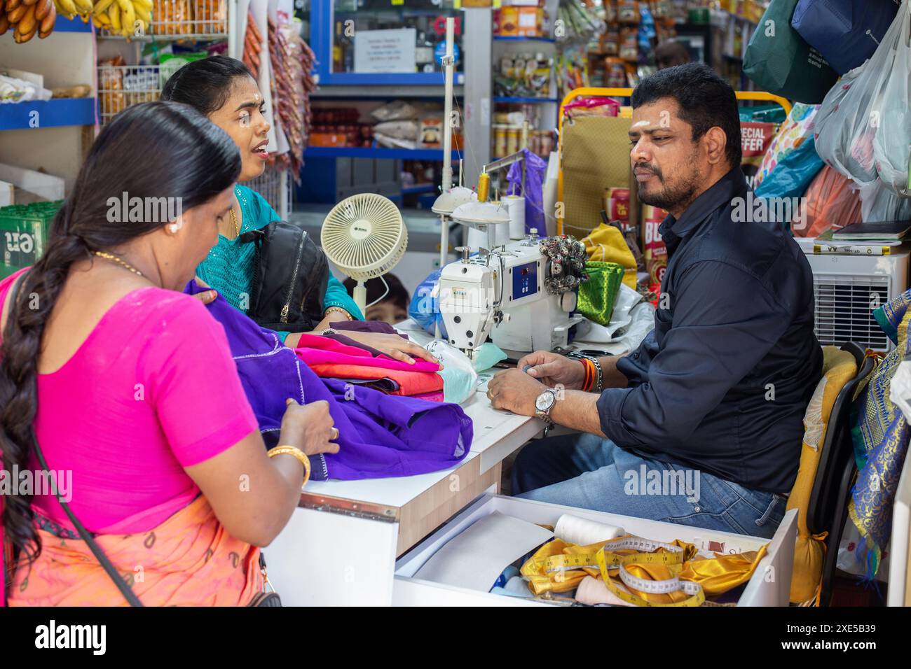 Sarto indiano che parla con le sue due clienti femminili vestono a Sari. Piccola India, Singapore. Foto Stock