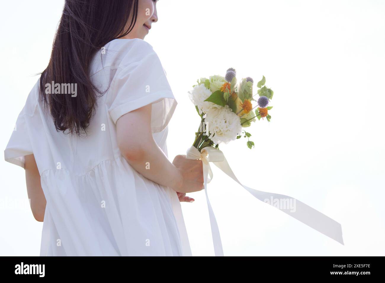 Giovane donna giapponese che indossa un vestito e tiene in mano un mazzo di fiori Foto Stock