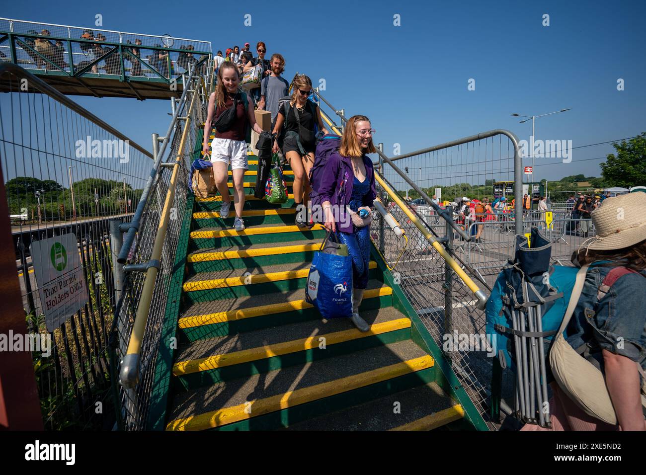 I festaioli arrivano alla stazione ferroviaria di Castle Cary mentre escono dalla piattaforma e sugli autobus che li porteranno al Glastonbury Festival presso la Worthy Farm nel Somerset. Data foto: Mercoledì 26 giugno 2024. Foto Stock