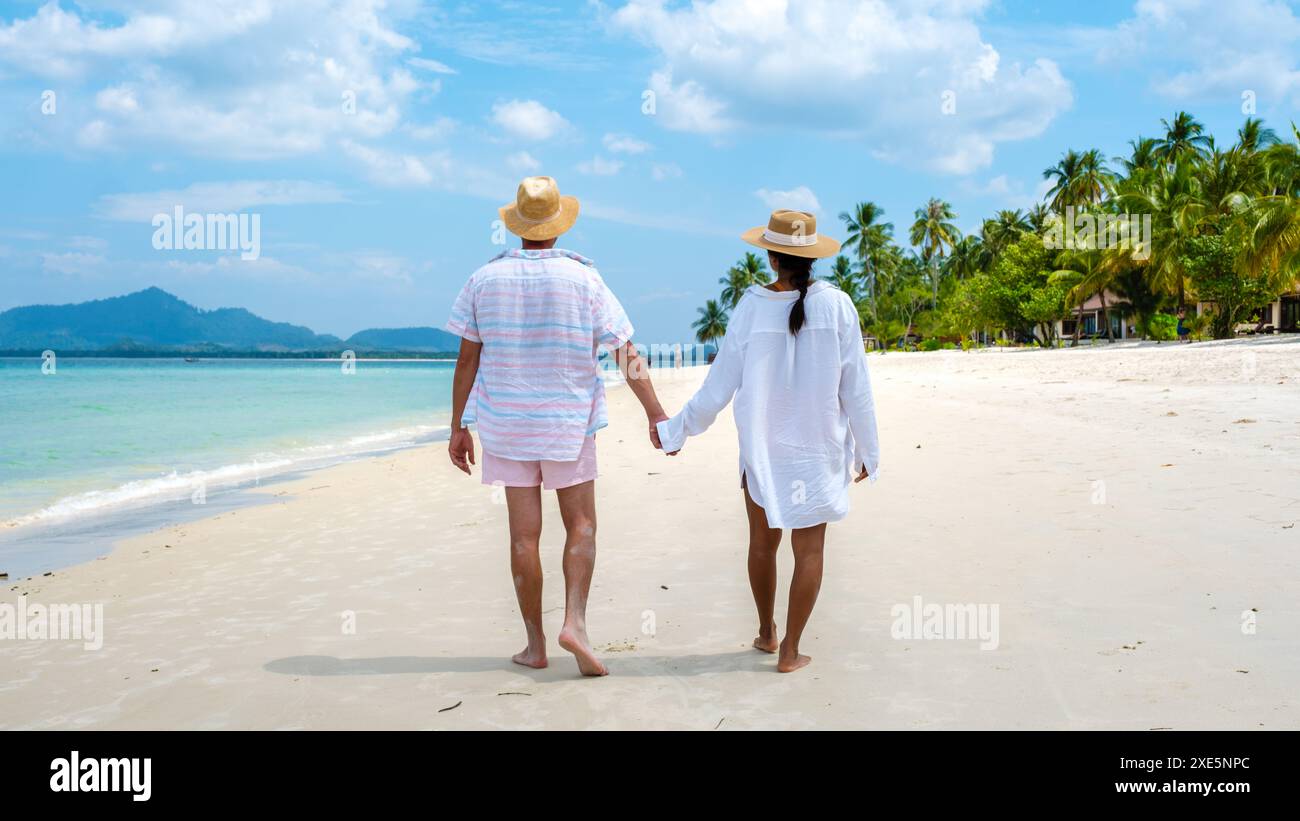 Koh Mook, una giovane coppia di uomini caucasici e una donna asiatica thailandese che cammina sulla spiaggia in Thailandia Foto Stock