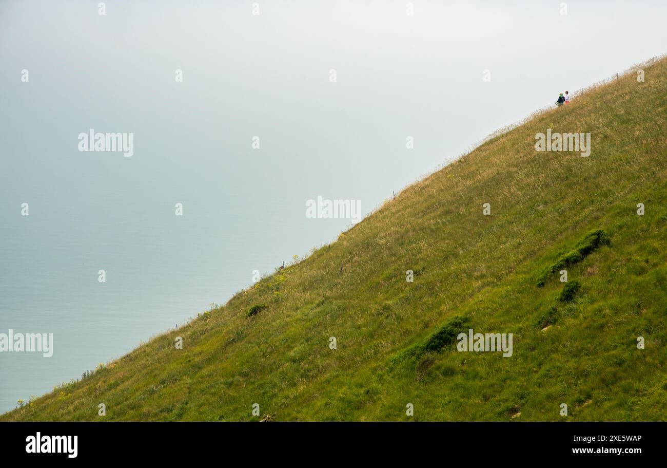 Persone che camminano al bordo di una scogliera verde lungo l'oceano a Mist. Persone attive all'aperto. Stile di vita sano Foto Stock