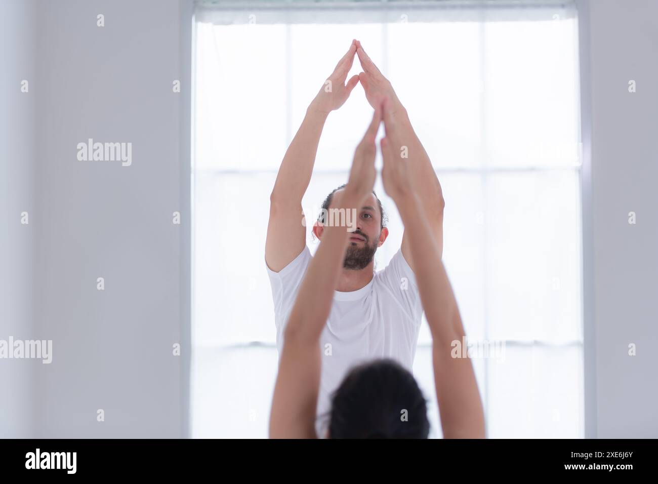 Giovane coppia che pratica yoga in una stanza bianca di studio. Foto Stock