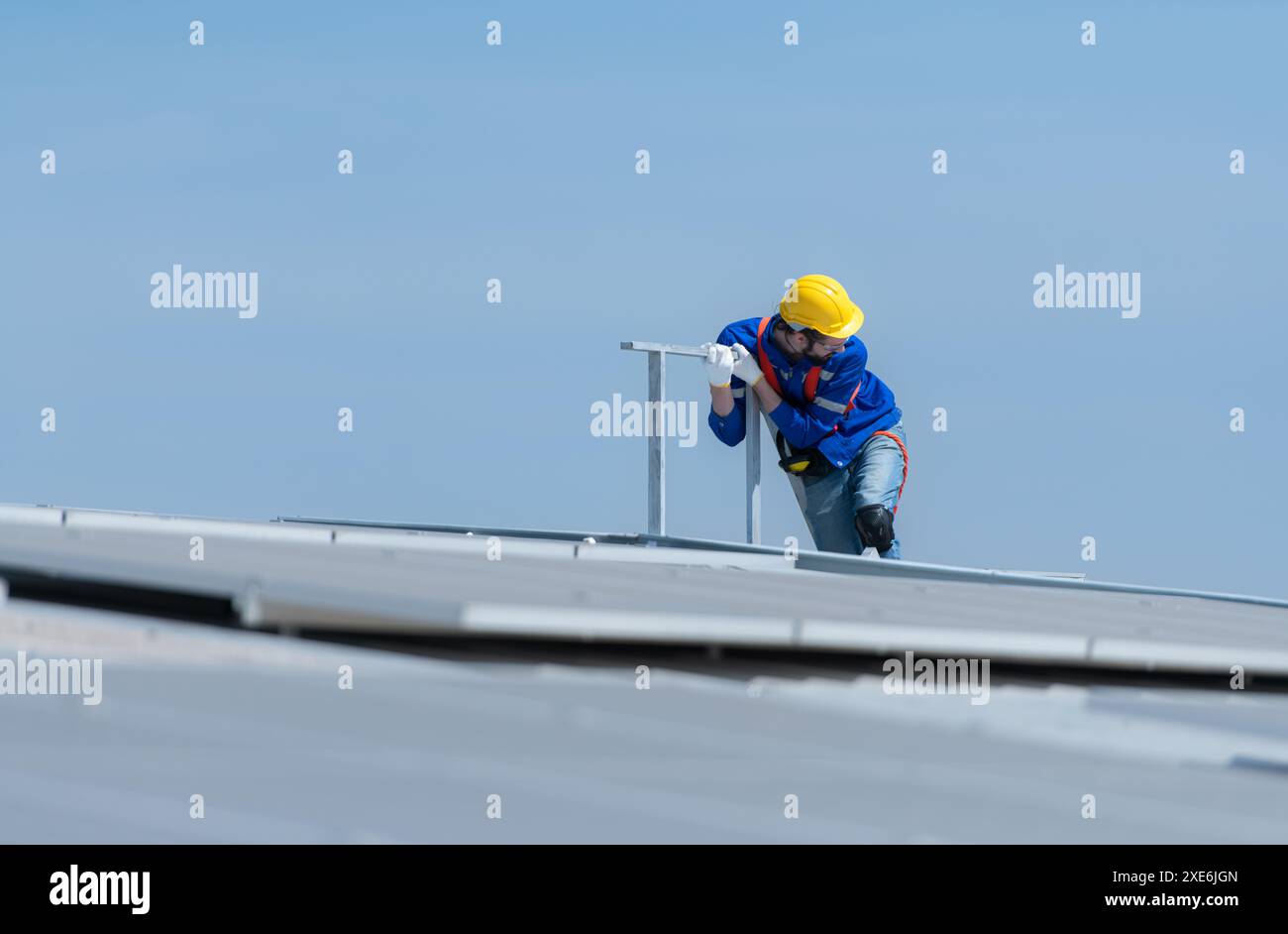 Un nuovo tecnico tirocinante che lavora sui pannelli solari con paura delle altezze Foto Stock