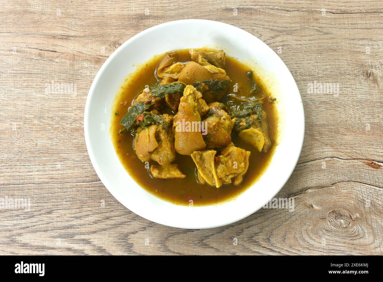 coscia di maiale piccante bollita con cumino e basilico in zuppa di curry al latte di cocco sul piatto Foto Stock