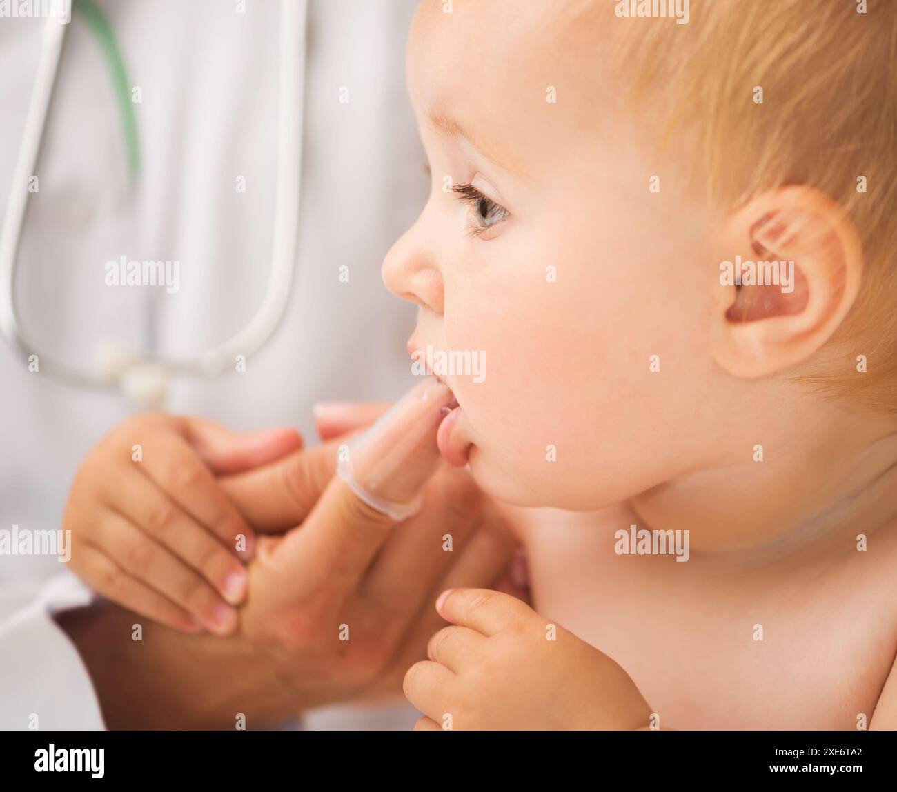 medico che pulisce la bocca del bambino con una spazzola speciale per i bambini Foto Stock