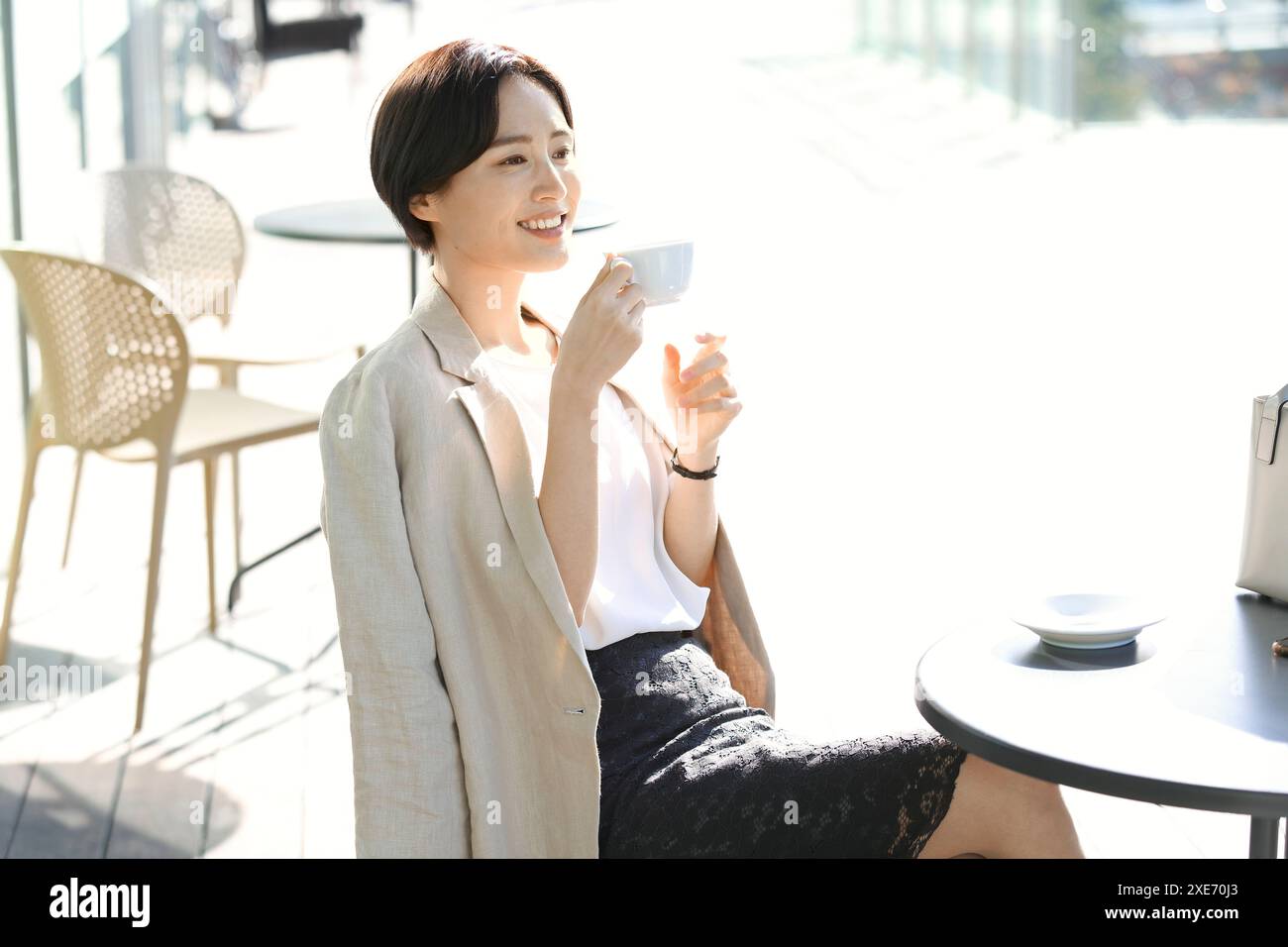 Donna giapponese che beve un caffè sulla terrazza del caffè Foto Stock