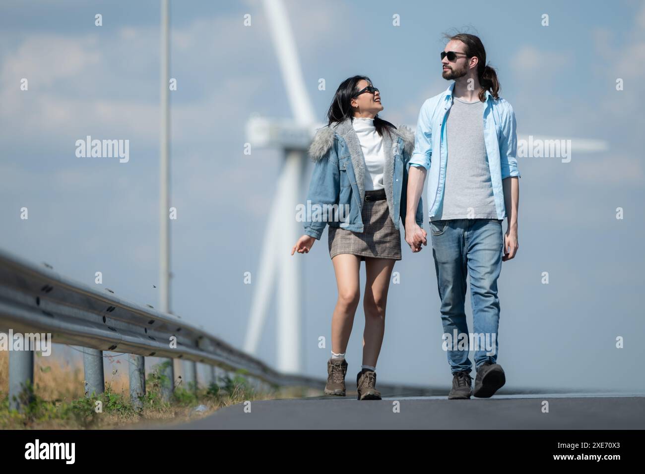 Giovani coppie che si rilassano vicino alla turbina eolica sul lago Foto Stock